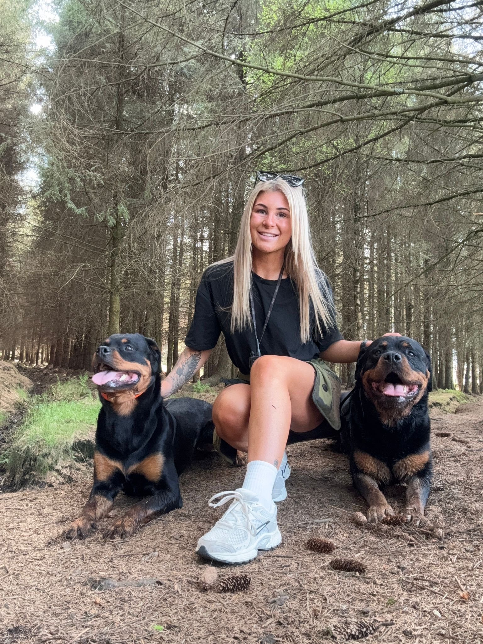 Ellie from Big Paw Little Paw with two Rottweilers in the woods